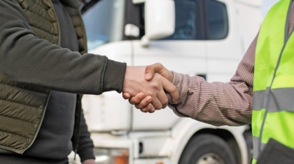 Aperto de mãos de 2 motoristas com um caminhão ao fundo