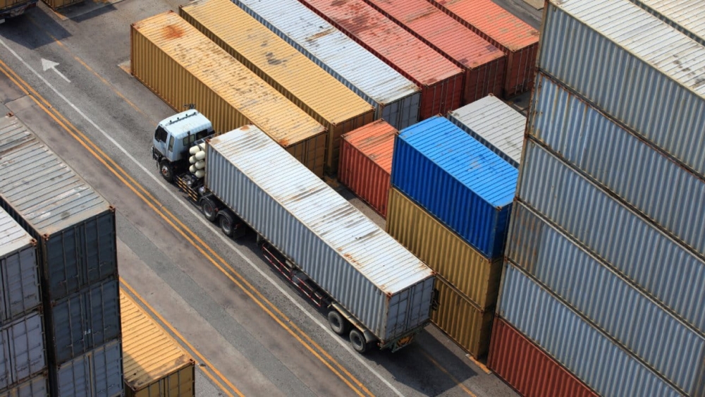 Caminhão passando próximo a contêineres de uma área de armazenagem
