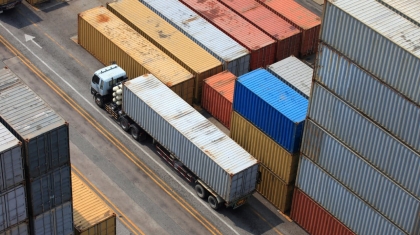 Caminhão passando próximo a contêineres de uma área de armazenagem