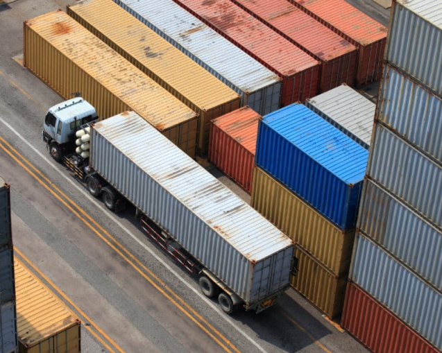 Caminhão passando próximo a contêineres de uma área de armazenagem