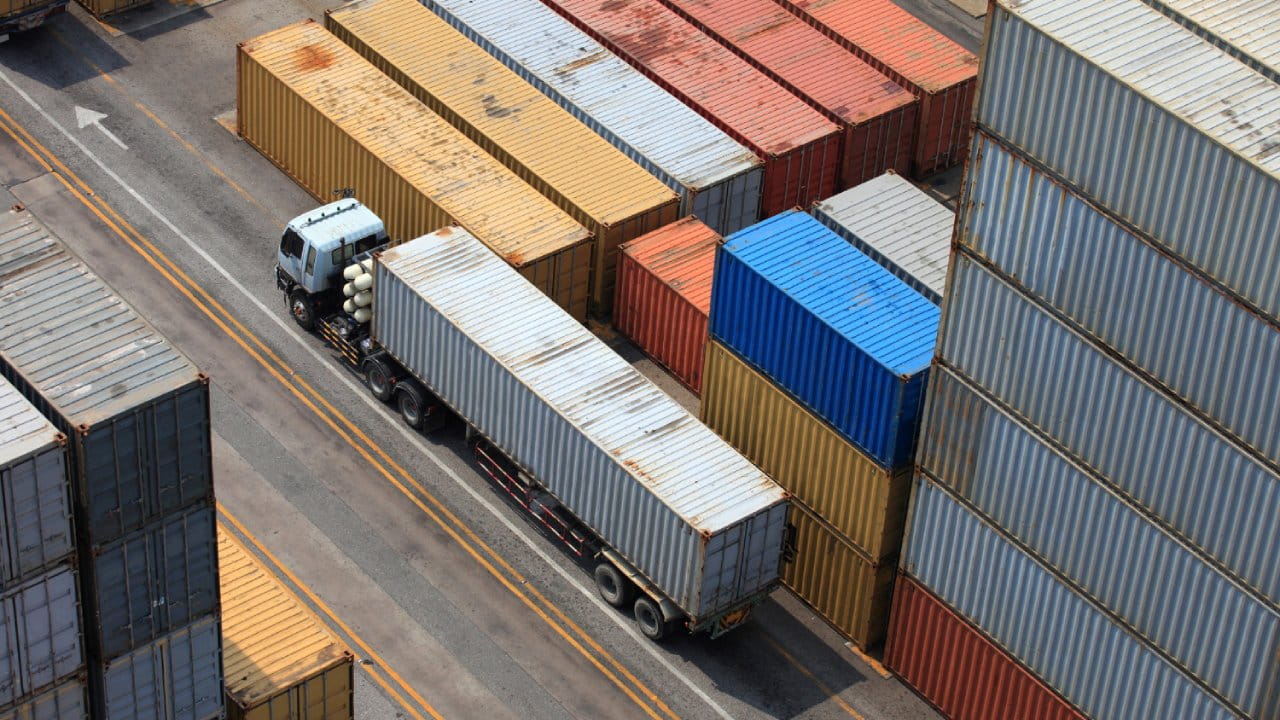 Caminhão passando próximo a contêineres de uma área de armazenagem